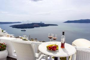 a table with two glasses of wine and a bowl of fruit at Santorini View Studios - Firostefani Caldera in Firostefani