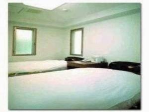 1 dormitorio con 2 camas, escritorio y 2 ventanas en Ikawa Ryokan, en Hiroshima