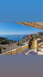 エズにあるSunny Panoramic Balconyの水辺の景色を望むバルコニーに立つ女性