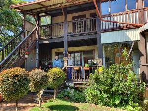 a man standing on the porch of a house at Kattekwaad Accommodation in Kaapsehoop