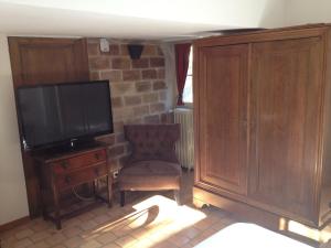 sala de estar con TV, silla y armario en Hotel L'Aunette Cottage, en Chamant