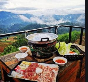 un piatto di cibo su un tavolo su un balcone con vista sulle montagne di ไร่นาบัวหลวง คาเฟ่ & ฟาร์มสเตย์ RaiNa BuaLuang Cafe & Farm Stay a Ban Na No