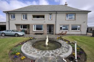 a house with a fountain in front of a house at Sandwick Bay Guest House in Stornoway