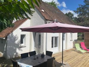 a patio with a table and an umbrella on a deck at Gîtes de charme dans l'Essonne in Buno-Bonnevaux