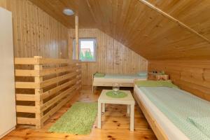 Cette chambre en bois comprend 2 lits et une table. dans l'établissement Kompleks Wypoczynkowy Bryza II, à Lubiatowo