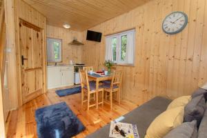 a living room with a table and a clock on the wall at Kompleks Wypoczynkowy Bryza II in Lubiatowo +15 photos