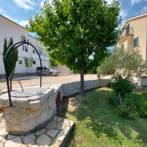 un arbre dans un mur de pierre à côté d'un bâtiment dans l'établissement Apartments Batistić, à Supetarska Draga