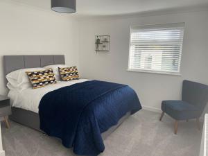 ein Schlafzimmer mit einem Bett mit einer blauen Decke und einem Stuhl in der Unterkunft Rhos Walia,near Snowdonia,Hot tub in Caernarfon
