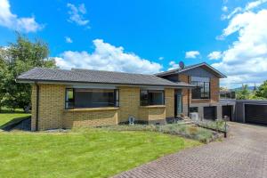 a brick house with a lawn in front of it at Spacious retreat with Mountain View in Rotorua
