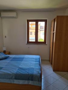 諾維格勒半島的住宿－Apartment Manuel，一间卧室设有蓝色的床和窗户。