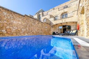 沙拉的住宿－Gozo Villa w/Private Pool near Beach + AC + BBQ，石头建筑前的游泳池