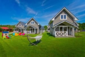 a house on a lawn with a swing at Kompleks Wypoczynkowy Bryza III in Lubiatowo