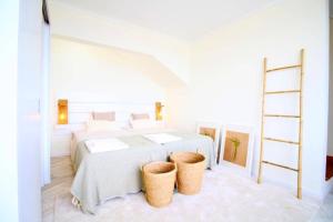 a white bedroom with a bed and two baskets at Fish House 3 in Prainha de Cima