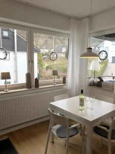 a dining room with a white table and chairs and windows at Ferienwohnung Gierse in Schmallenberg