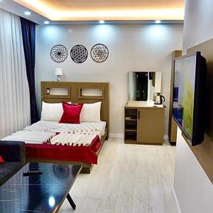 a bedroom with a bed with red pillows and a television at Konyaaltı HOTEL in Antalya