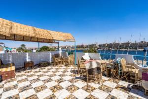 a patio with chairs and tables and a view of the water at Nubian Paradise in Aswan