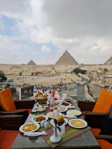 Hayat Pyramids View Hotel في القاهرة: طاولة عليها طعام مع الاهرامات في الخلفية