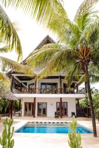 a villa with a swimming pool and palm trees at Tamani Villas in Matemwe