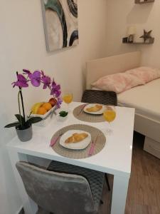 a white table with two plates of food and drinks at Studio apartman Megy in Sutivan