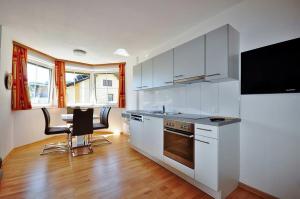 a kitchen with white cabinets and a table with chairs at Appartements Peter in Sankt Kanzian