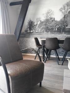 ein Wohnzimmer mit Stühlen, einem Tisch und einem Fenster in der Unterkunft De Bedstee in Holwerd