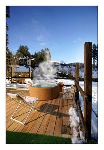 a hot tub on a deck with two chairs and snow at Il Rifugio del Risol in Castione della Presolana