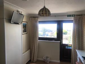 a living room with a television and a window at Stoke House Bed and Breakfast in Stoke Rivers