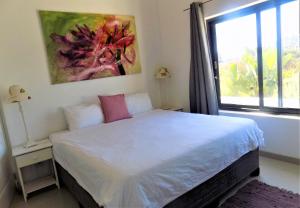 1 dormitorio con 1 cama con una pintura en la pared en Green Goose self catering villa with pool, en Plettenberg Bay
