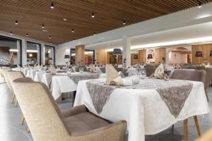 un comedor con mesas y sillas blancas en Hotel Bucaneve, en Livigno