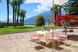 a table with pink chairs and an umbrella at Palazzina GiardinoLago in Gravedona