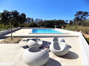 una piscina con 3 grandes esculturas blancas al lado en Green Goose self catering villa with pool, en Plettenberg Bay