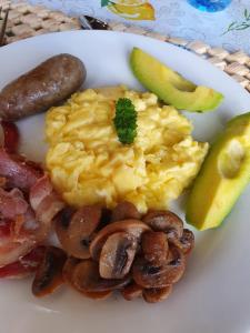 a plate of breakfast food with eggs bacon mushrooms and a pickle at Kattekwaad Accommodation in Kaapsehoop