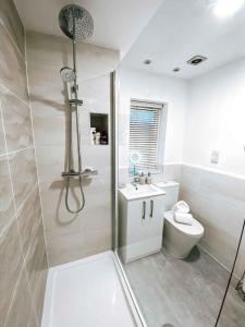 a white bathroom with a shower and a toilet at Sutton Heath Lodge in Saint Helens