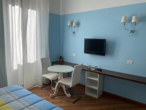 um quarto com uma secretária e uma televisão numa parede azul em Luna Rossa Roma Guest House em Roma