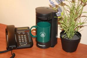 una taza de café verde sentada junto a un teléfono y una maceta en University of Alberta - Hotel, en Edmonton