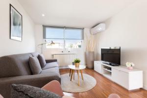 een woonkamer met een bank en een tv bij Sitges Group Beach Dreams in Sitges