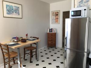 een keuken met een tafel en een roestvrijstalen koelkast bij Gites Jardin-darcy in Bois