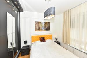 Schlafzimmer mit einem Bett mit einem orangefarbenen Kopfteil in der Unterkunft Grand Lux apartman in Čačak