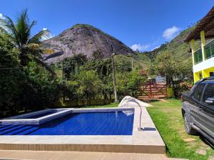 a swimming pool in front of a house with a mountain at Sítio do Rodeadouro in Bonito