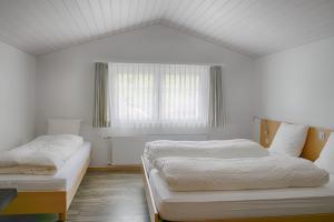 a white bedroom with two beds and a window at Loosmühle in Weissbad