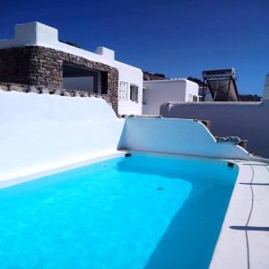 una piscina con agua azul frente a una casa en 4BD Blue Dream Mykonos, en Mykonos ciudad