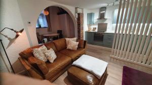 a living room with a brown couch and a kitchen at Chambers Apartment @ The Old Magistrates in Betws-y-coed