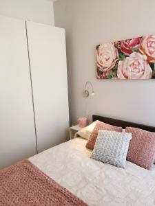 una camera da letto con un letto con cuscini rosa e un dipinto di Apartment Heart of Old Town a Pola (Pula)