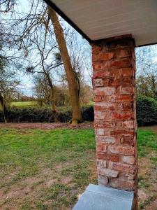 a brick wall in a yard with a tree at Covenham Holiday Cottages in Covenham