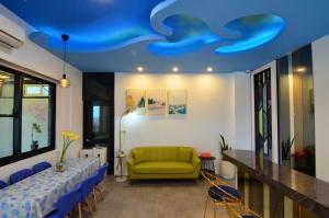 een kamer met een blauw plafond, een bank en een tafel bij Haipai Sweetheart Homestay in Magong