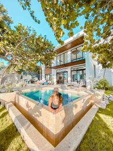 a woman sitting in front of a swimming pool at Bay Shore 76 in Palmar de Ocoa