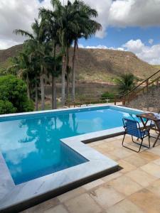 a swimming pool with a table and a chair at Casa Amarela - 3 suítes e piscina in Piranhas