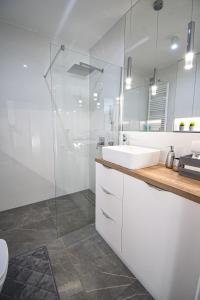 y baño con lavabo y ducha acristalada. en Apartament VILLA PARK przy plaży z widokiem na jezioro, taras 50 m2, en Ostróda