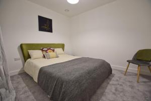 um quarto com uma cama com uma cabeceira verde e uma cadeira em Coastal Links em Portrush