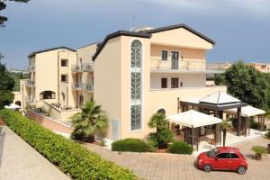 czerwony samochód zaparkowany przed budynkiem w obiekcie Hotel Villa Rosa w mieście Martina Franca